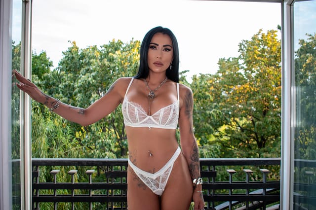 Mistress Kennya stands on a balcony during a solo fetish scene captured in 4K resolution with immersive VR POV camera angles.